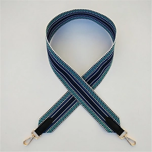 Close-up of geometric striped woven strap with gold metal hooks and black leather ends