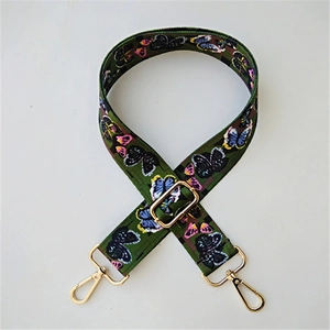 Macro shot of dark green nylon strap with colorful butterfly print and gold metal hooks