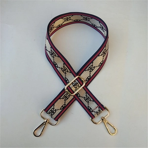 Detail of wide woven bag strap with classic stripe pattern and golden metal buckles