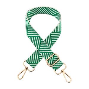 Detail of wide woven bag strap with green and white twill pattern and gold metal hooks