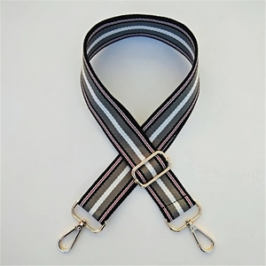 Close-up of adjustable striped handbag strap with golden metal hooks and buckles