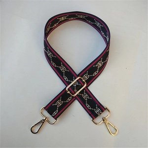 Close-up of adjustable wide woven bag strap with golden hardware and H-pattern embroidery