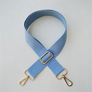 Detalle de correa ajustable de algodón azul claro con hebillas y ganchos de metal dorado