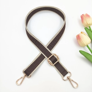 Close-up of adjustable woven shoulder strap with geometric pattern and gold metal hooks