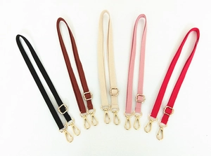 Detail of adjustable bag straps in black, brown, beige, pink, and red with gold hooks
