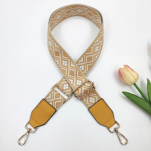 Detail of adjustable geometric jacquard bag strap with yellow faux leather and gold hooks