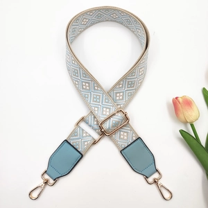Macro detail of blue geometric jacquard bag strap with gold buckle and tulip decoration