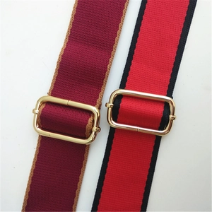 Close-up of adjustable fabric bag straps with gold buckles in red and burgundy colors
