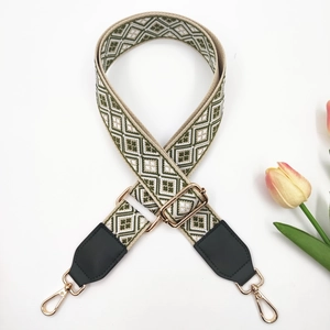 Detail of colorful geometric woven bag strap with black leather ends and gold hardware