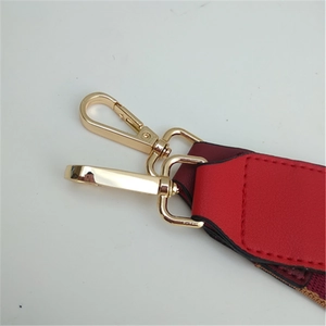 Detail of adjustable bag strap with red leather connector and gold lobster clasps