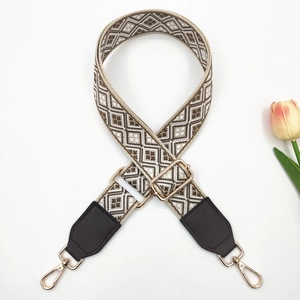 Detail of colorful jacquard wide bag strap with brown leather and gold buckles