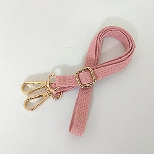 Detail of pink cotton strap with gold lobster clasps and adjustable metal buckle