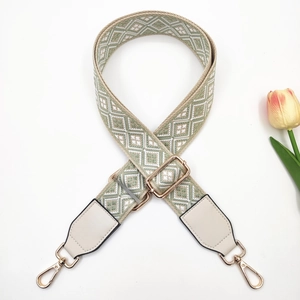 Detail of green geometric woven bag strap with adjustable gold buckle and leather ends
