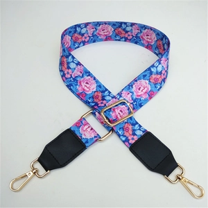 Close-up of blue floral bag strap with pink flowers and gold metal swivel hooks
