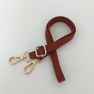 Close-up of brown canvas shoulder strap with adjustable buckle and gold lobster clasps