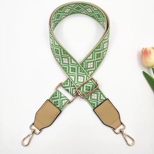 Close-up of geometric embroidered bag strap with gold metal hooks and faux leather ends