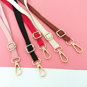 Detailed view of adjustable woven cotton shoulder straps with gold metal hardware hooks