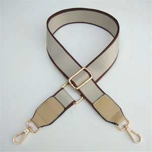 Adjustable beige fabric bag strap with brown leather ends and gold metal hardware
