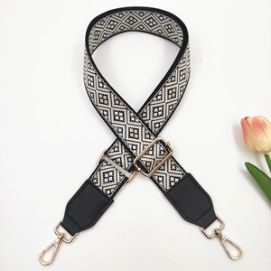 Detail of adjustable geometric jacquard bag strap with black leather and gold hardware