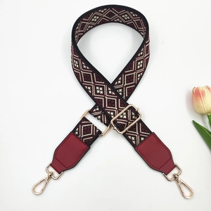 Detail of colorful jacquard guitar style bag strap with gold metal hooks and red leather
