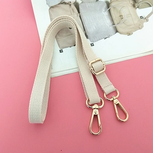 Close-up of beige woven cotton shoulder strap with polished gold metal swivel hooks