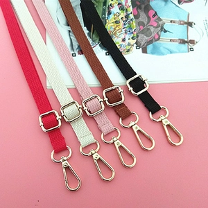 Detail of five colorful adjustable canvas bag straps with shiny gold metal hardware clips