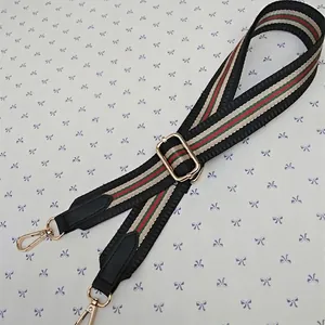 Close-up of adjustable woven shoulder strap with iconic red and green stripes and gold hooks