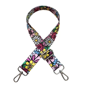 Detail of adjustable wide canvas bag strap with colorful daisy floral print and silver clips