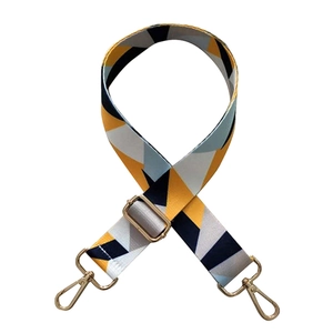 Detail of adjustable bag strap with yellow and grey geometric pattern and gold hooks