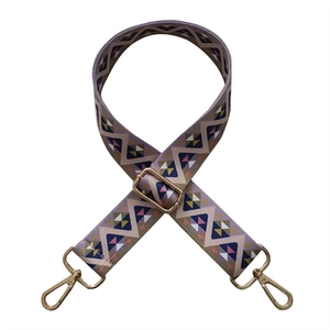 Close-up of bohemian wave patterned adjustable wide bag strap with gold metal buckles