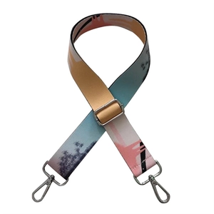 Close-up of adjustable wide bag strap with colorful abstract art patterns and silver buckles