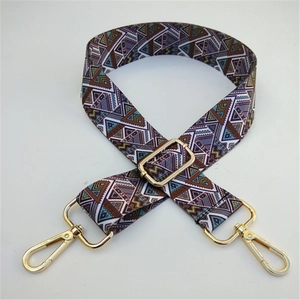 Close-up of ethnic style woven bag strap with purple geometric patterns and gold clips