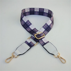 Detail of adjustable purple plaid woven strap with white leather ends and gold metal clips