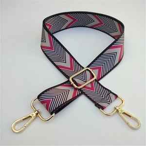 Close-up of woven geometric strap with pink and grey patterns and gold metal buckles