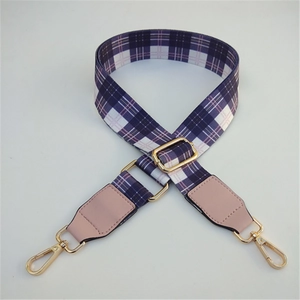 Detail of purple plaid replacement bag strap with golden metal buckles and pink leather ends