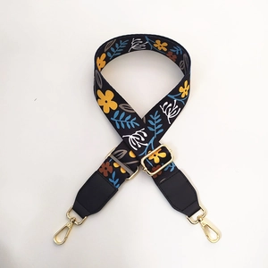 Detail of adjustable floral canvas strap with gold hardware and black leather ends