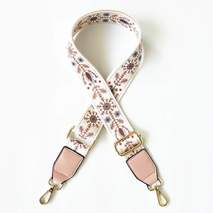 Close-up of ethnic embroidered bag strap with snowflake patterns and gold metal clips