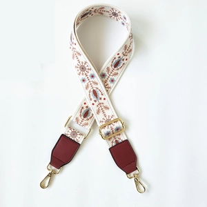 Close-up of ethnic embroidered bag strap with gold metal buckles and red leather details