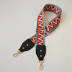 Close-up of ethnic style wide woven shoulder strap with red patterns and gold lobster clasps