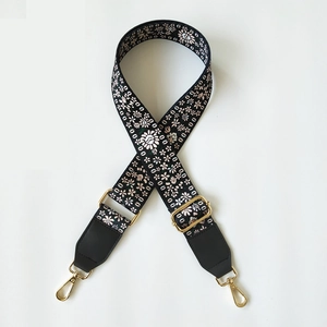 Close-up of floral jacquard strap with gold metal lobster clasps and black leather ends