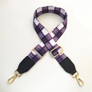 Macro shot of purple and pink plaid purse strap with gold metal hooks and black leather
