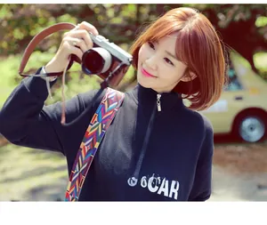 Detail of wide woven camera strap with colorful ethnic patterns and brown leather buckle