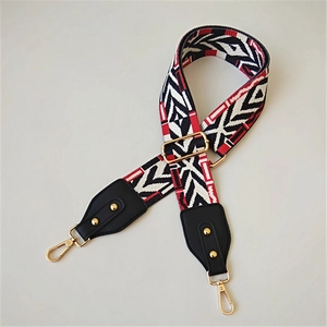Detail of red and black geometric woven purse strap with gold metal lobster clasps