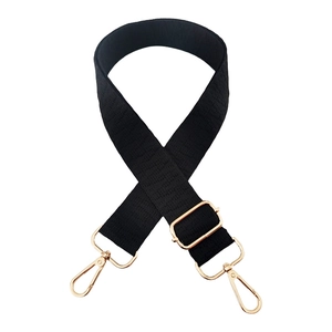 Detail of adjustable black woven bag strap with textured pattern and gold metal hooks