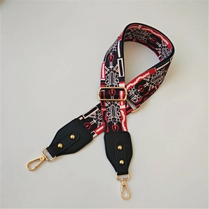 Close-up of red and black ethnic geometric jacquard guitar strap with gold swivel hooks