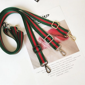 Close-up of adjustable striped canvas bag straps with three metallic finish clips
