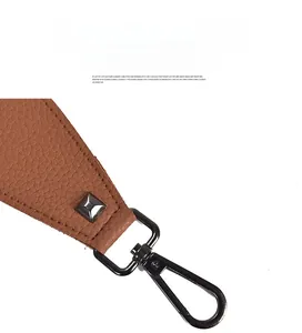 Macro view of brown lychee grain leather bag strap with metal rivet and lobster clasp