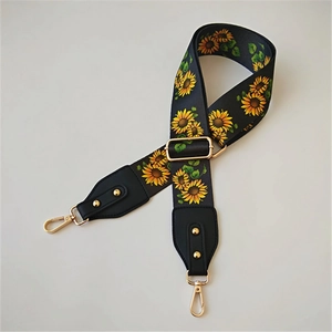 Detail of adjustable wide bag strap featuring sunflower print and gold metal swivel hooks