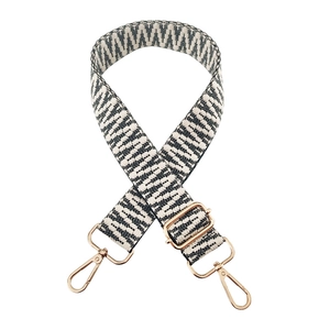 Close-up of black and white geometric woven bag strap with golden metal swivel hooks