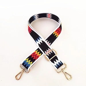 Detail of adjustable wide woven bag strap with colorful geometric pattern and gold hooks